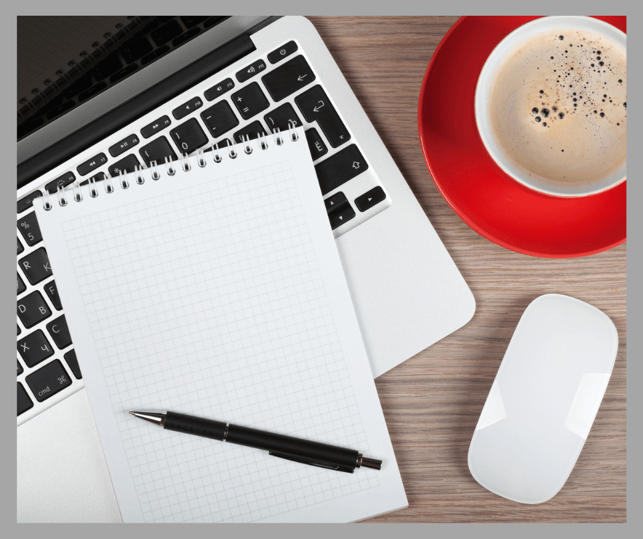 Blank notebook laying on a computer with a coffee cup