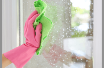 A hand in a pink glove washing a window.
