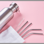 Reusable straws in a pouch with a bottle on a pink background