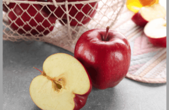 A basket of apples with a cut apple in front of the basket