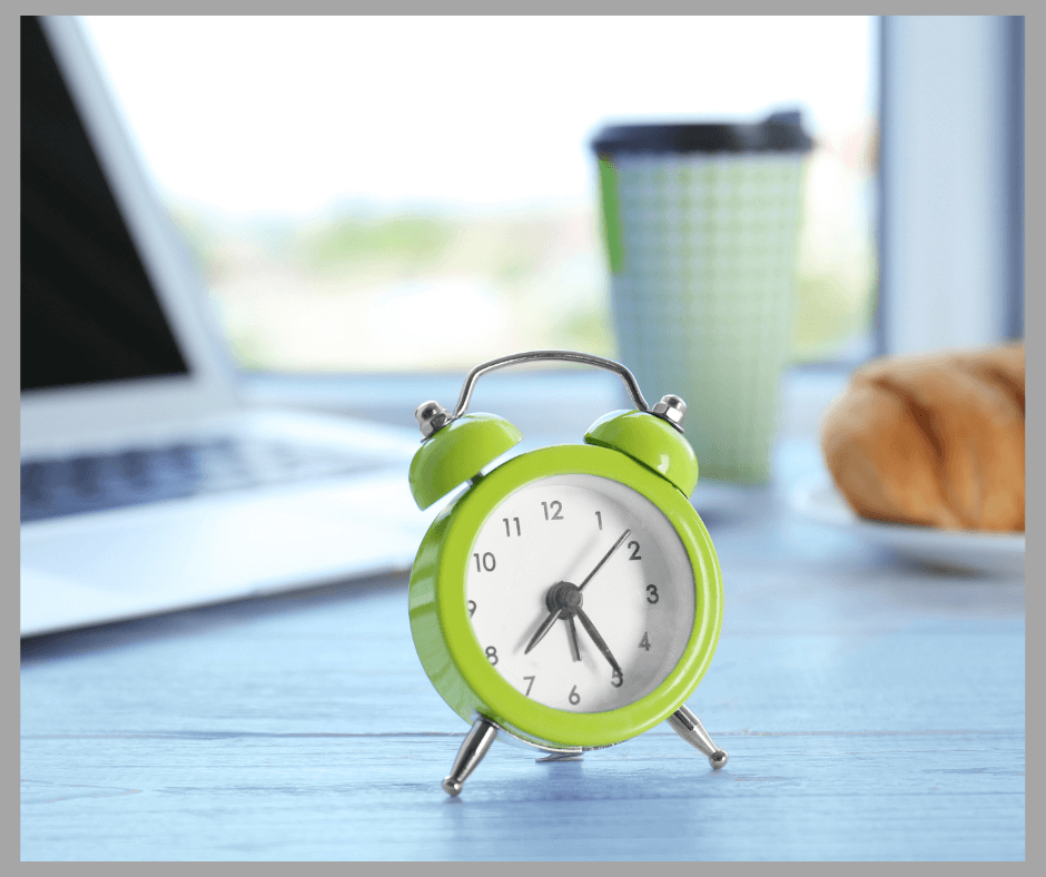Bright green alarm clock with a computer, a cup, and a loaf of bread