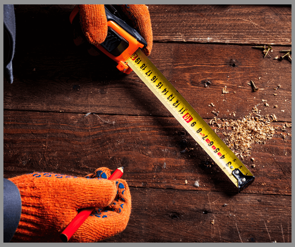 A carpenter using a yellow tape measure