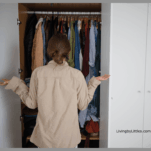 A Lady standing outside of a closet looking for something to wear.