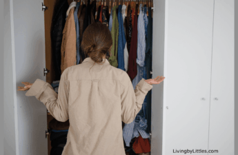 A Lady standing outside of a closet looking for something to wear.