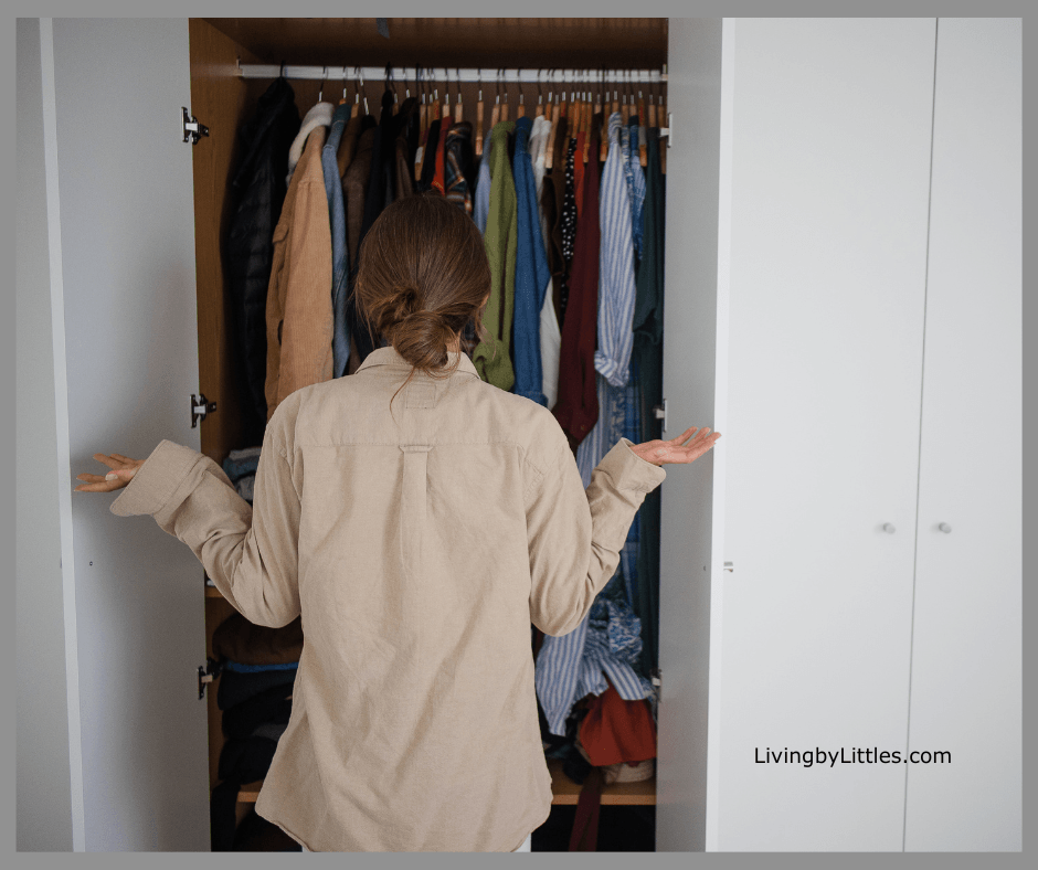 A Lady standing outside of a closet looking for something to wear.